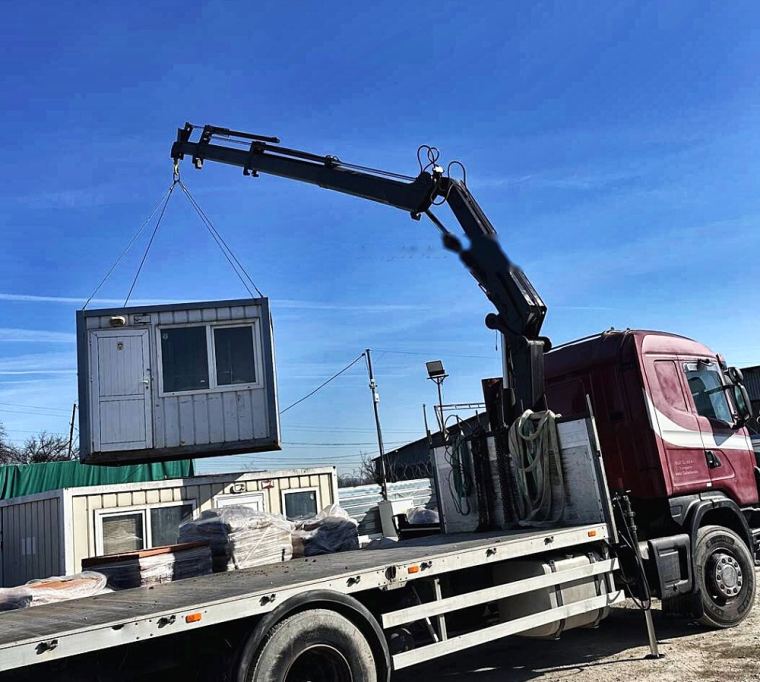Камион с кран разтоварва фургон на строителен обект